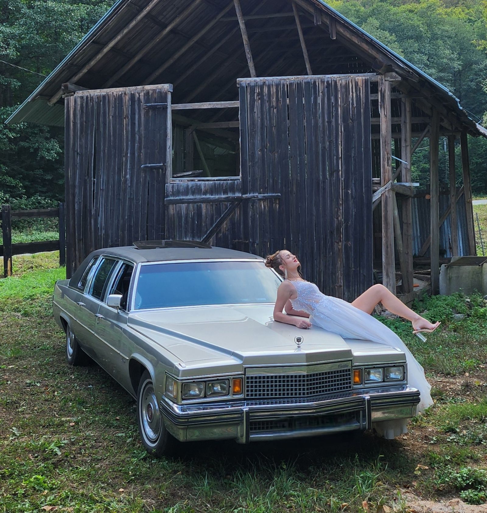 Nevesta ležiaca na kapote Cadillacu Fleetwood pri drevenej stodole