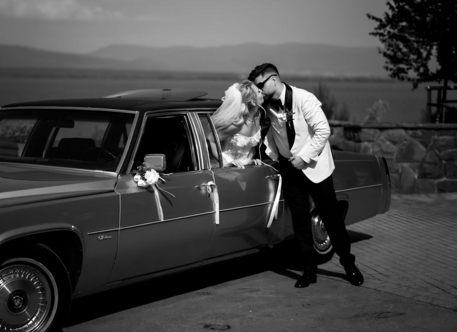 Bozk novomanželov pri Cadillacu, čiernobiela svadobná fotografia